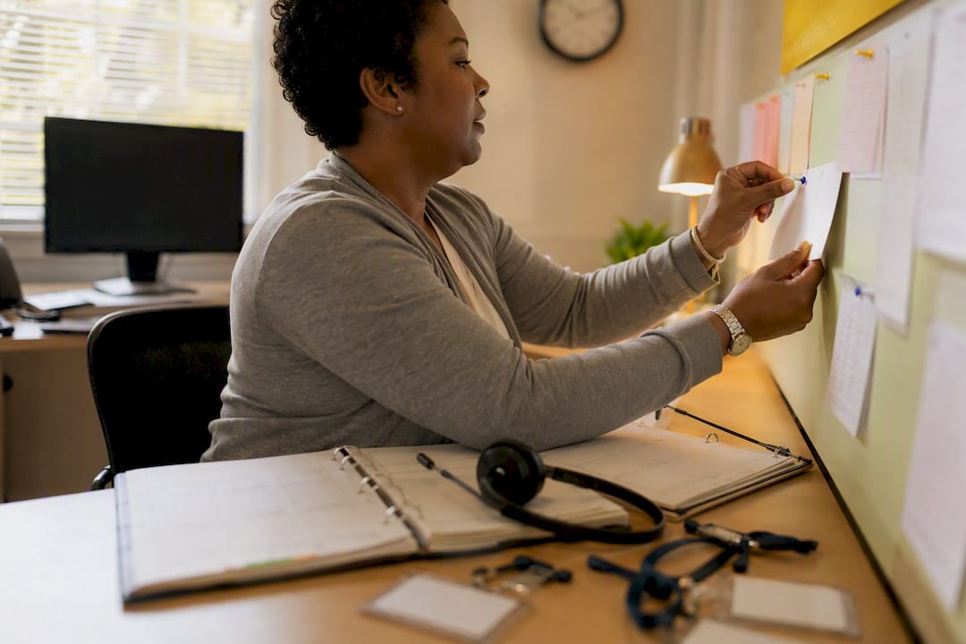 Hands arranging caregiver schedule notes on desk