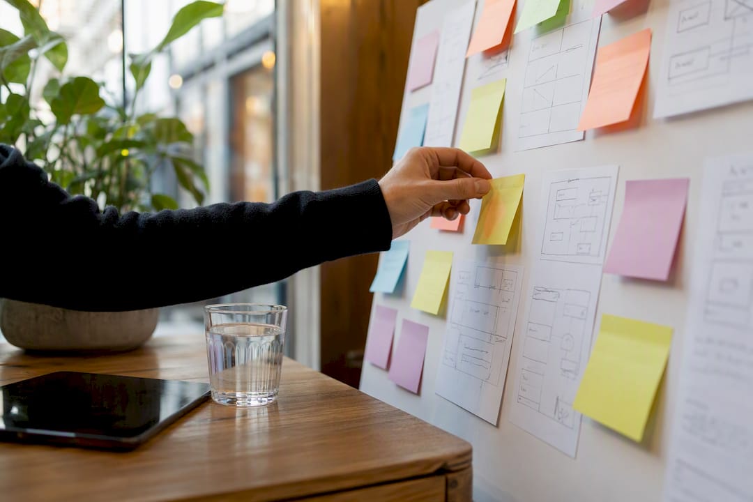 Hand placing sticky notes on planning board