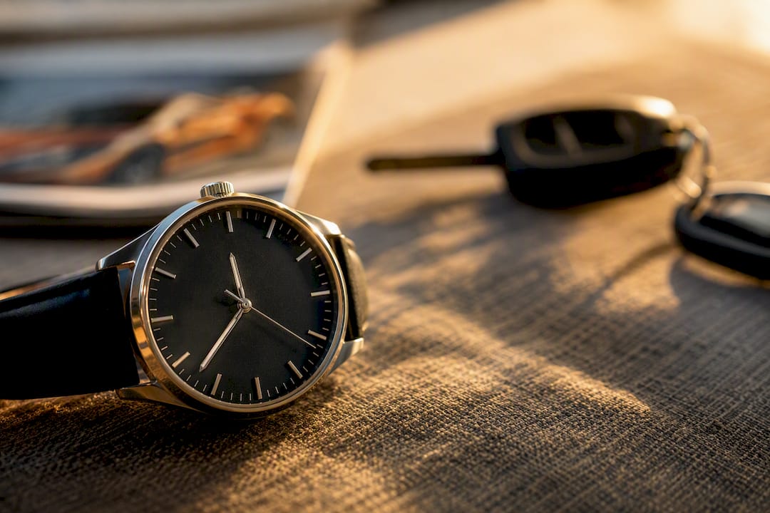 Gros plan sur le cadran d'une montre et une clé de voiture floue