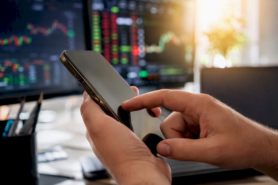 Un trader qui cède à la tentation et achète des cryptos sur un coup de tête depuis son smartphone.