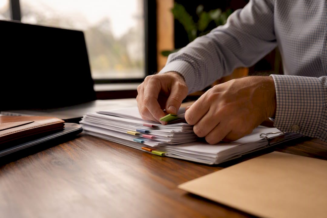 Hands tagging financial documents with tabs
