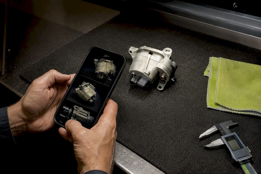Hands photographing a stamped automotive part number