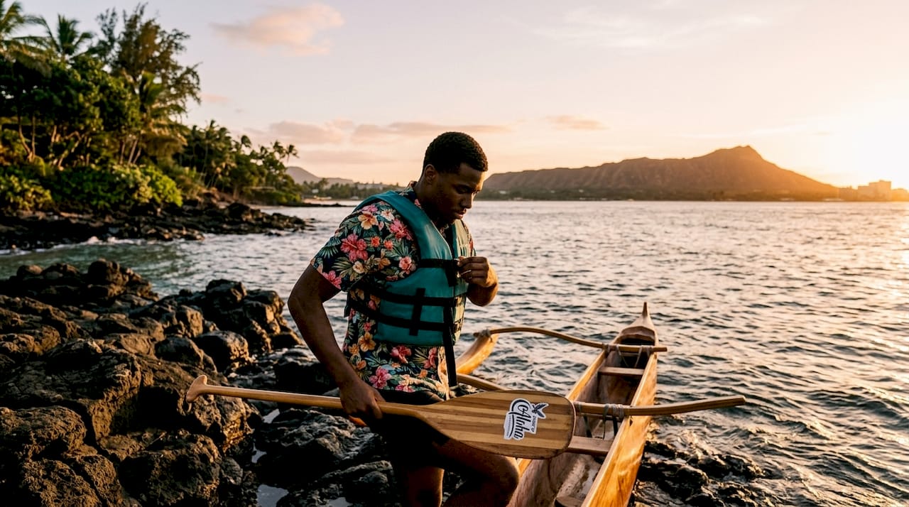 Young man boarding outrigger canoe at Kona beach