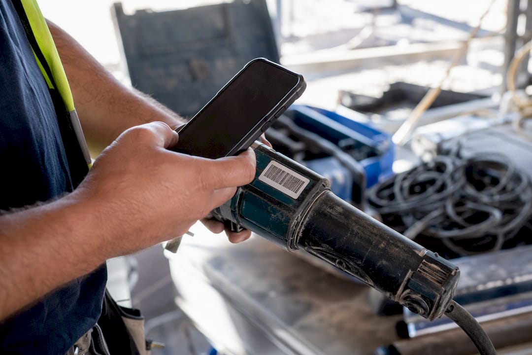 Hand scanning barcode on tool with smartphone