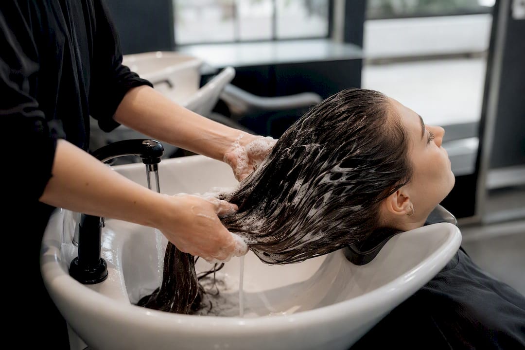 Hands washing hair extensions under water