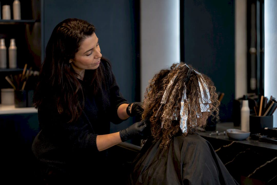 Stylist sectioning curly hair for color correction