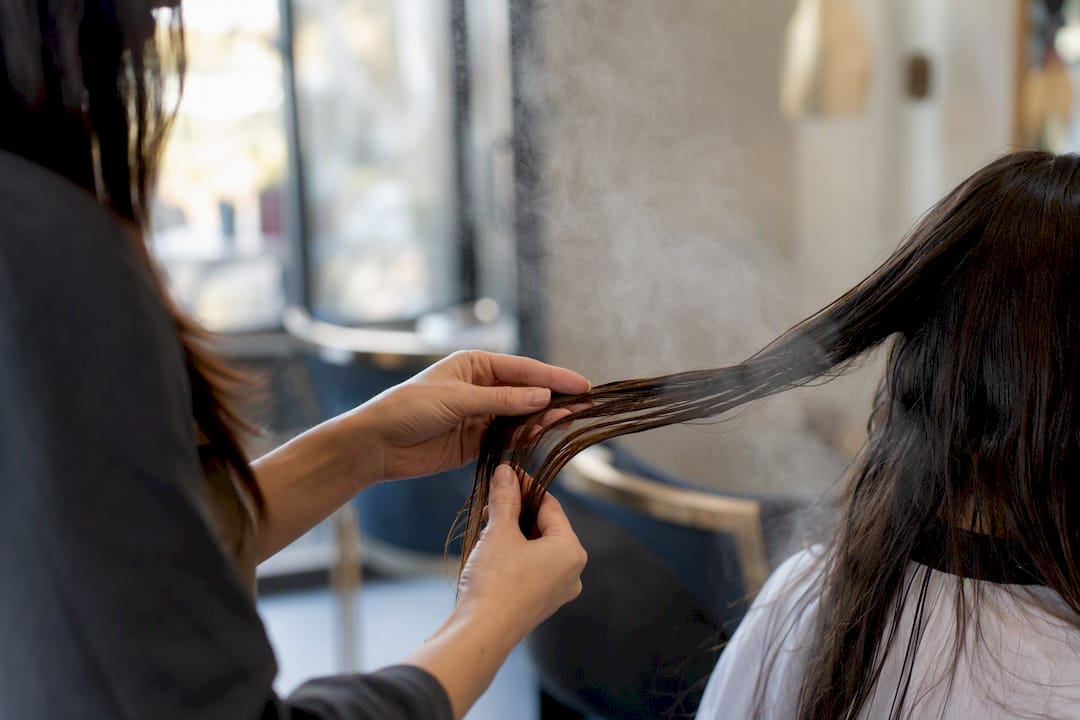 Hands assessing hair steam treatment