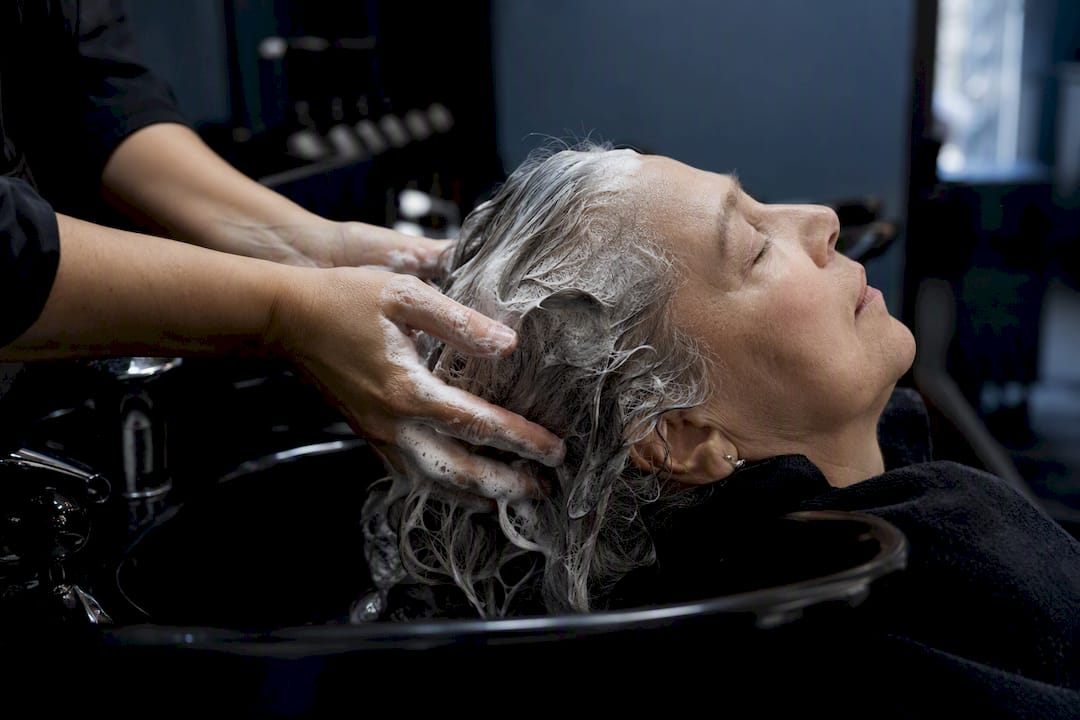 Stylist applying silver shampoo on grey hair