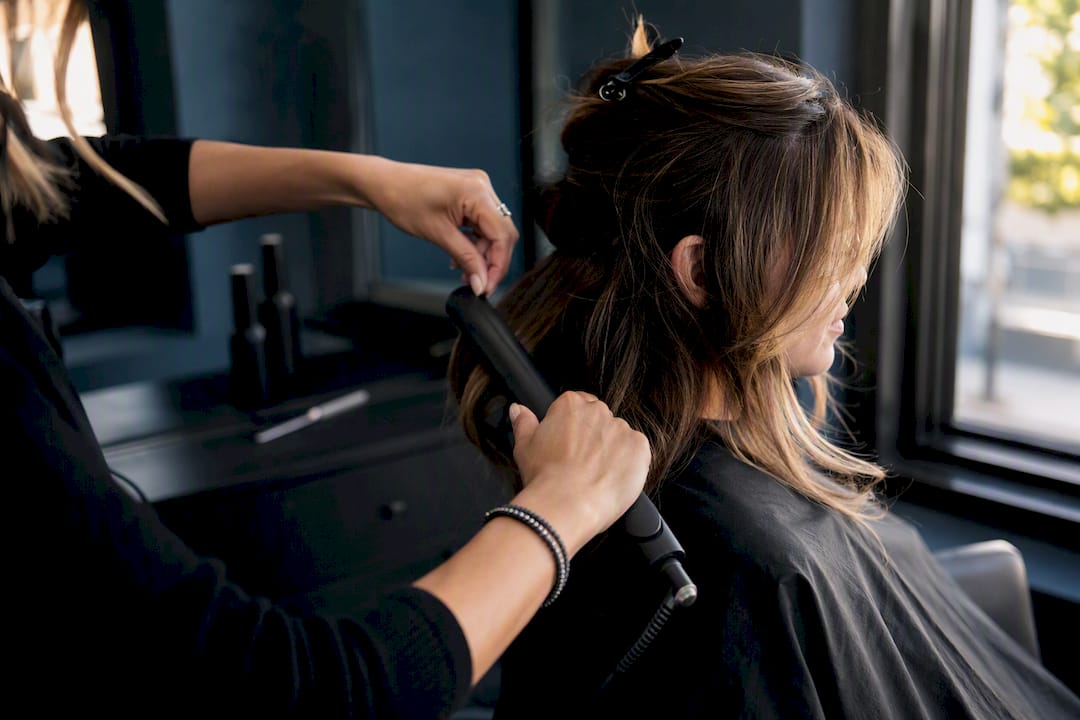 Hands styling face-framing layers with brush and dryer