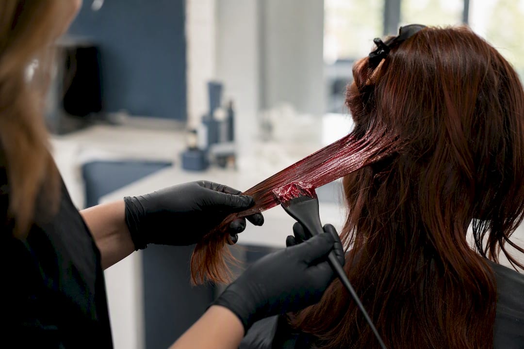 Stylist applying red dye on hair cuticle