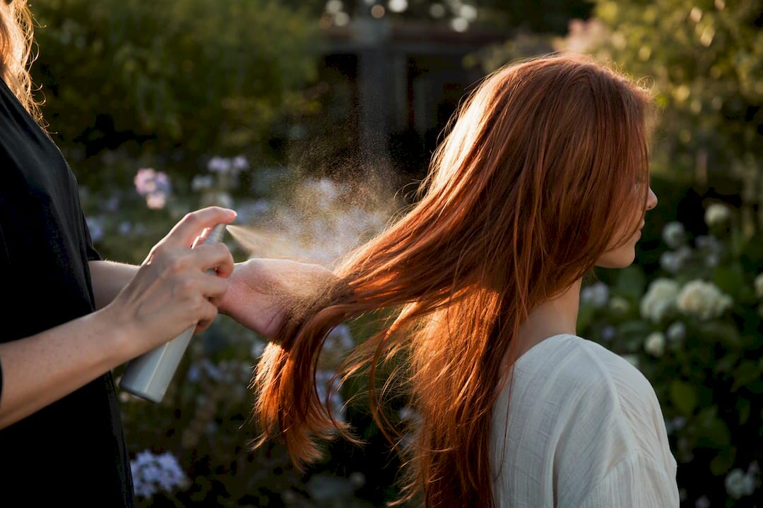 Applying UV protection spray on red hair