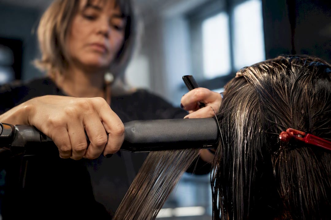 Stylist sealing hair with a flat iron