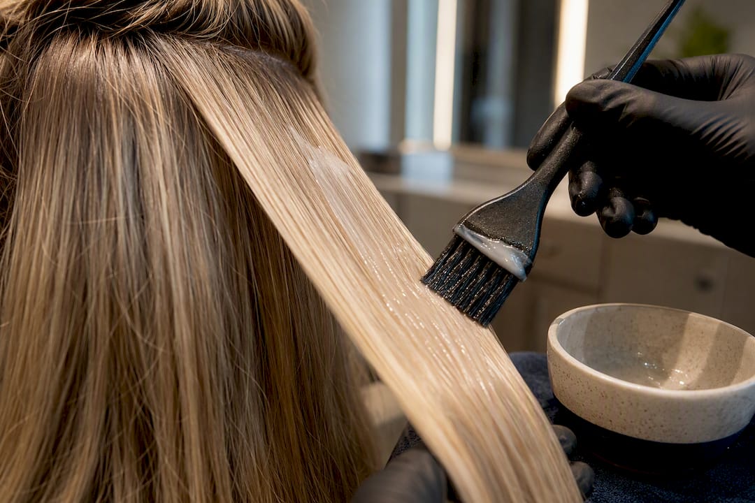 Colorist applying gloss to blonde hair