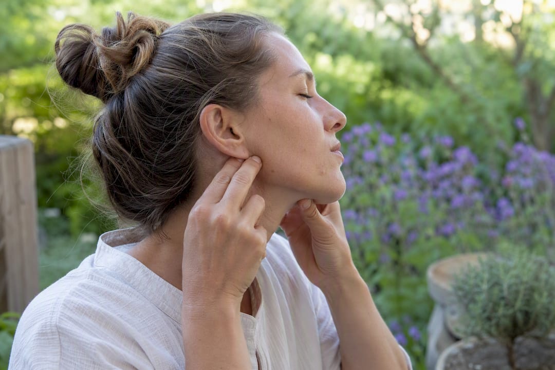Fingers pressing masseter muscle on jaw