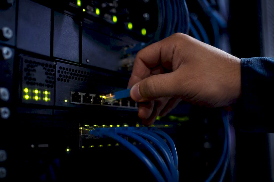 Hand, die ein Kabel im Serverraum verbindet