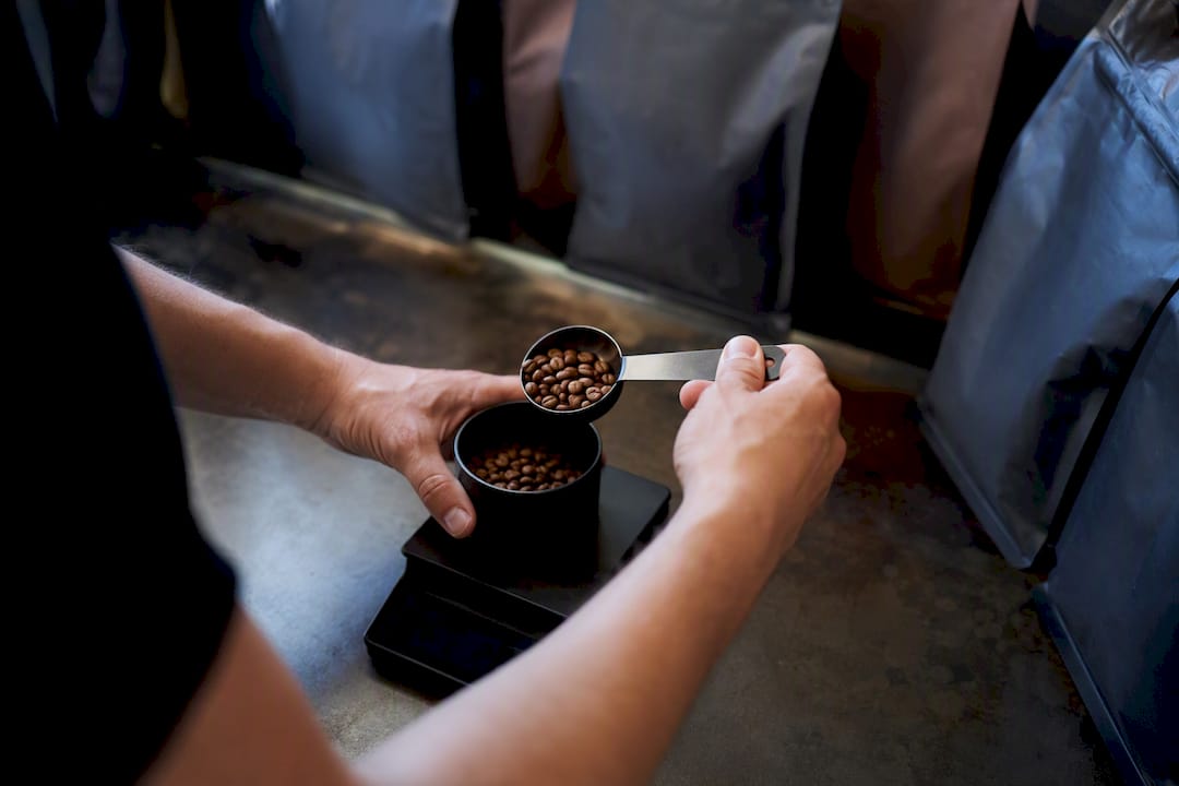 Hands weighing coffee beans on scale