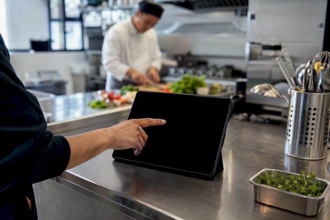 Hand interacting with smartphone in catering kitchen