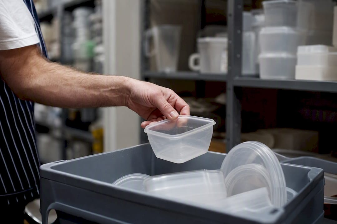 Hand placing empty allergen container in bin
