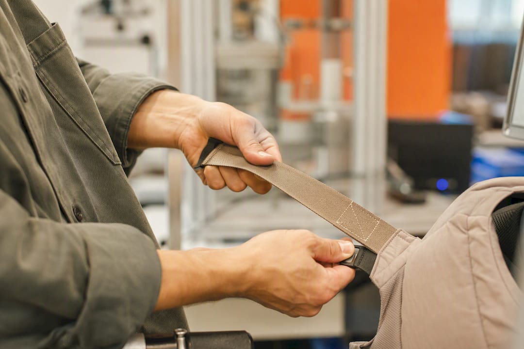 Hands stretching baby carrier straps during static testing