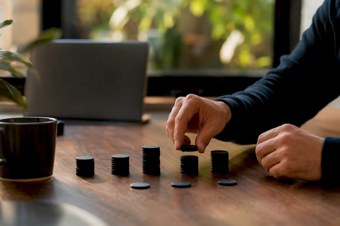 Hands adjusting budget tokens on desk