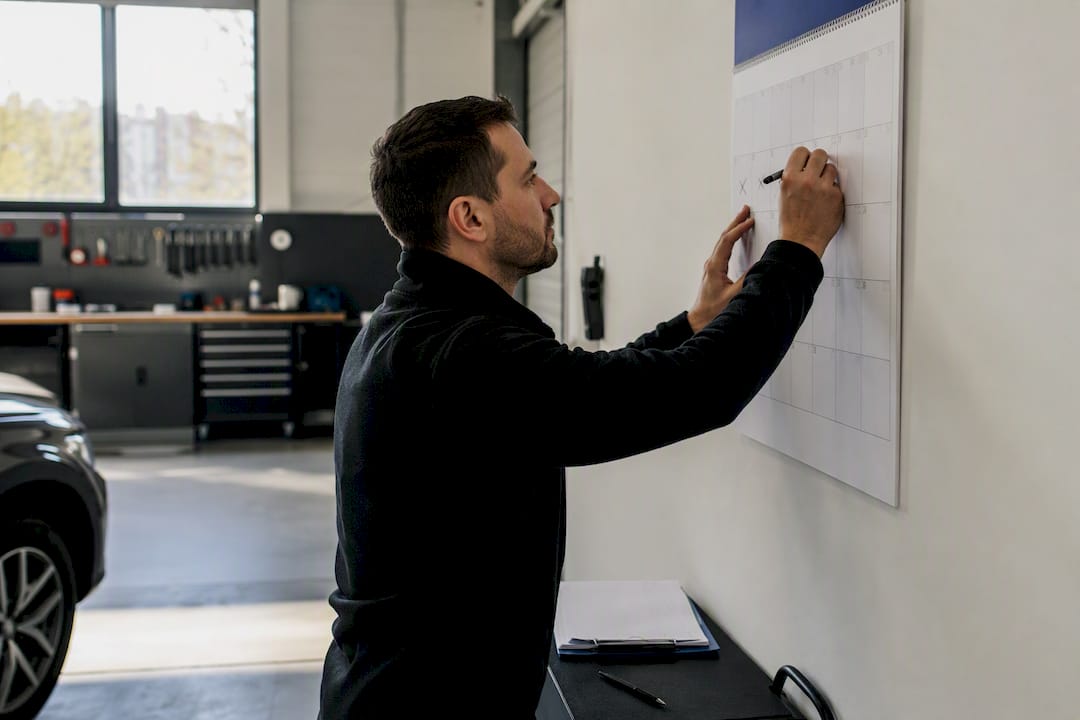 Hände markieren ein Datum im Dezember im Werkstattkalender