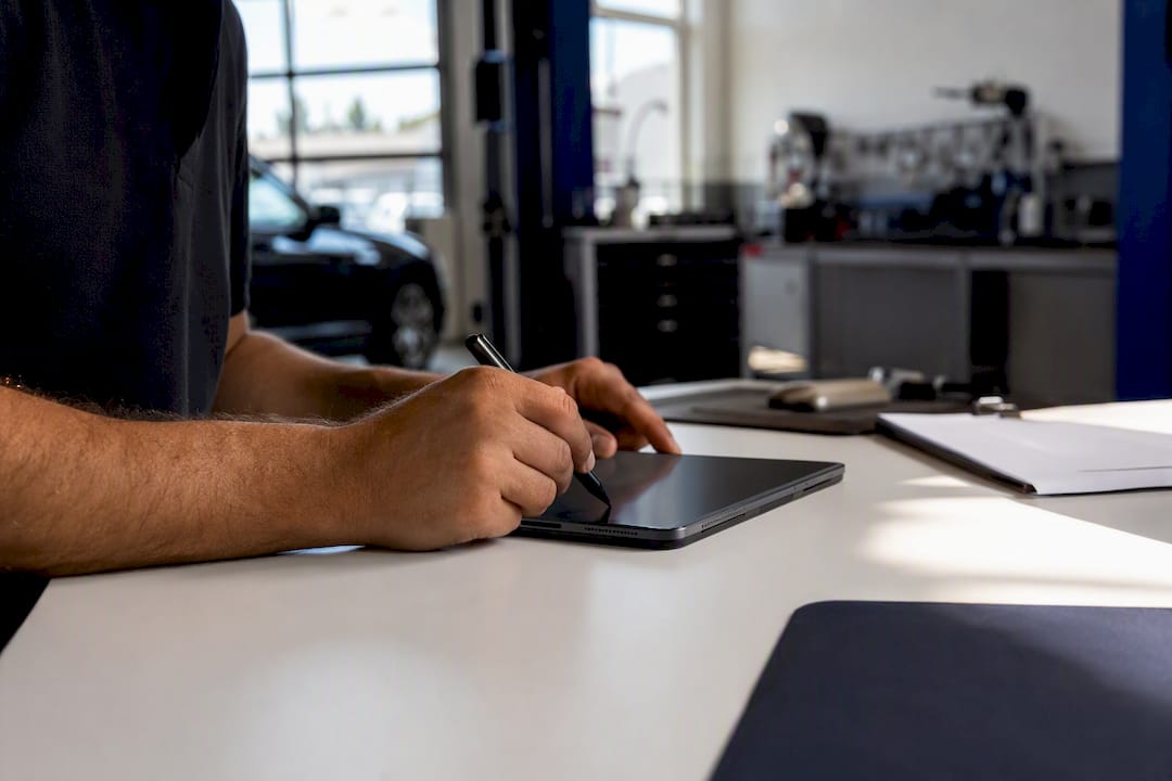 Hände, die eine Rechnung digital auf einem Tablet unterschreiben
