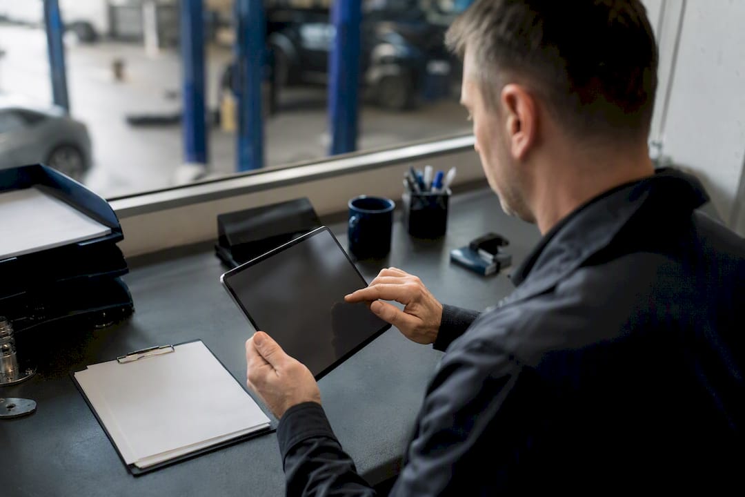 Hände richten ein digitales Abrechnungsgerät in der Werkstatt ein