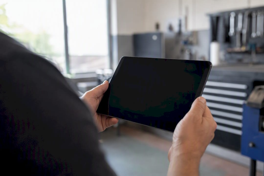 Hände halten ein Tablet im Werkstattbüro