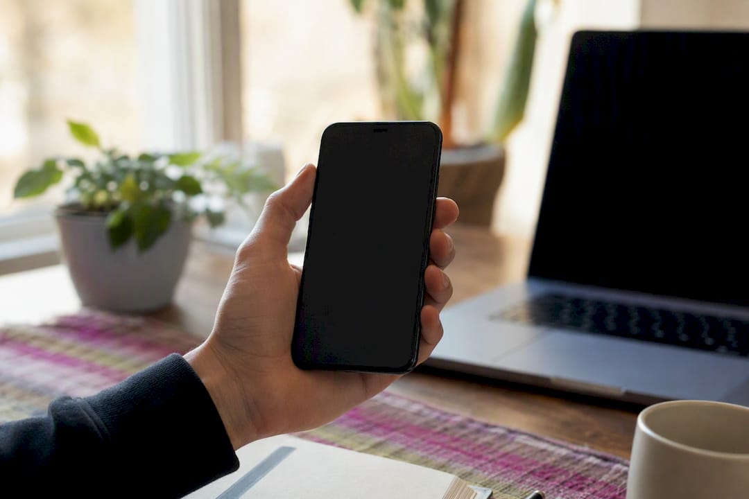 Hand holding smartphone with cracked phone screen background