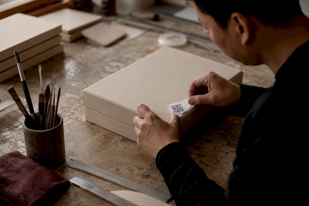 Artisan applying QR code label to luxury box