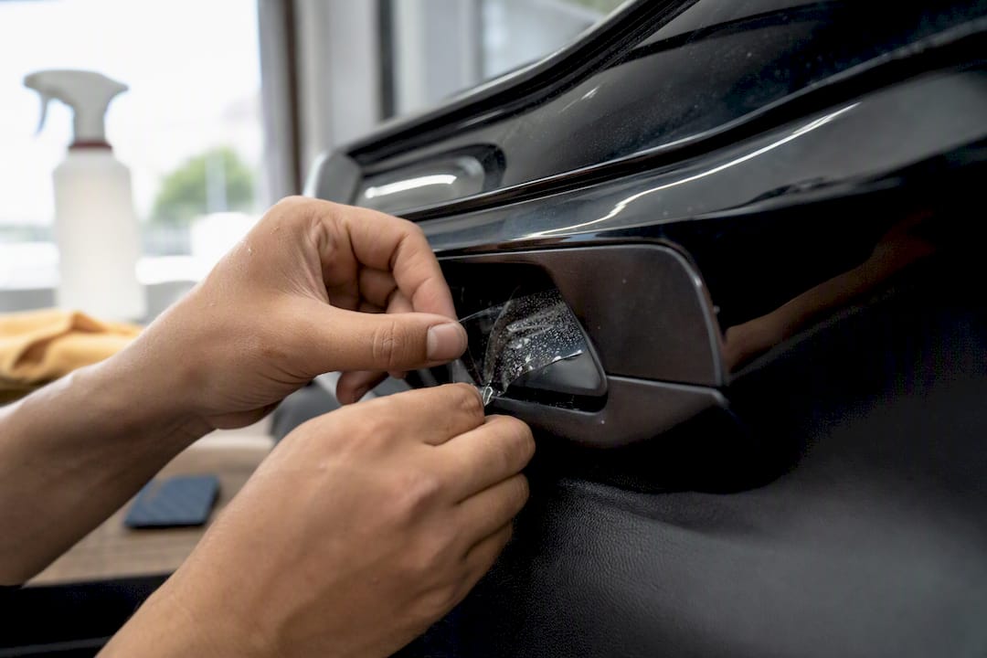 Hands installing door cup paint protection film