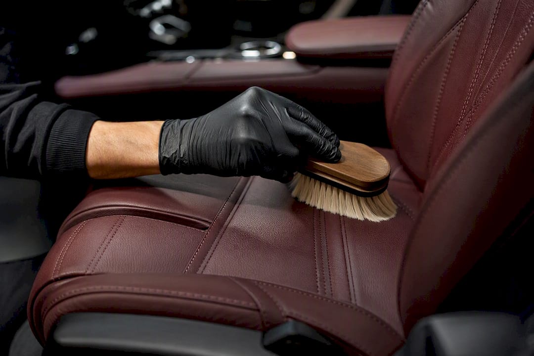 Gloved hand cleaning luxury leather car seat