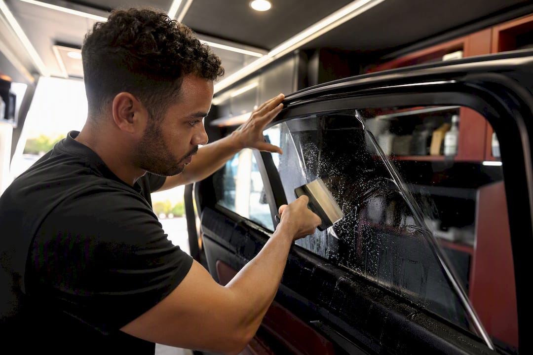 Hands applying ceramic tint to car window