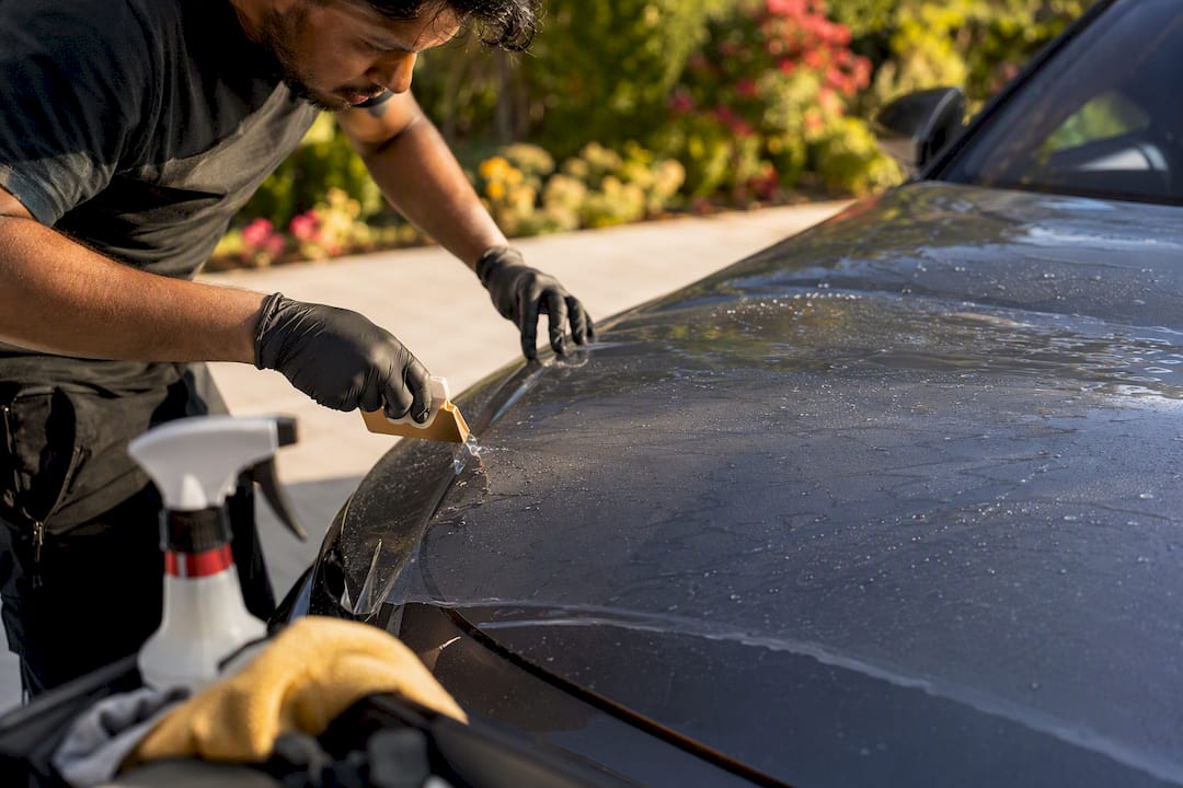 Detailer applying paint protection film on car hood