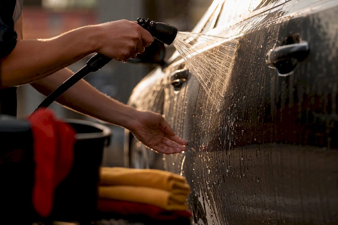 Technician rinsing car door to remove mineral deposits