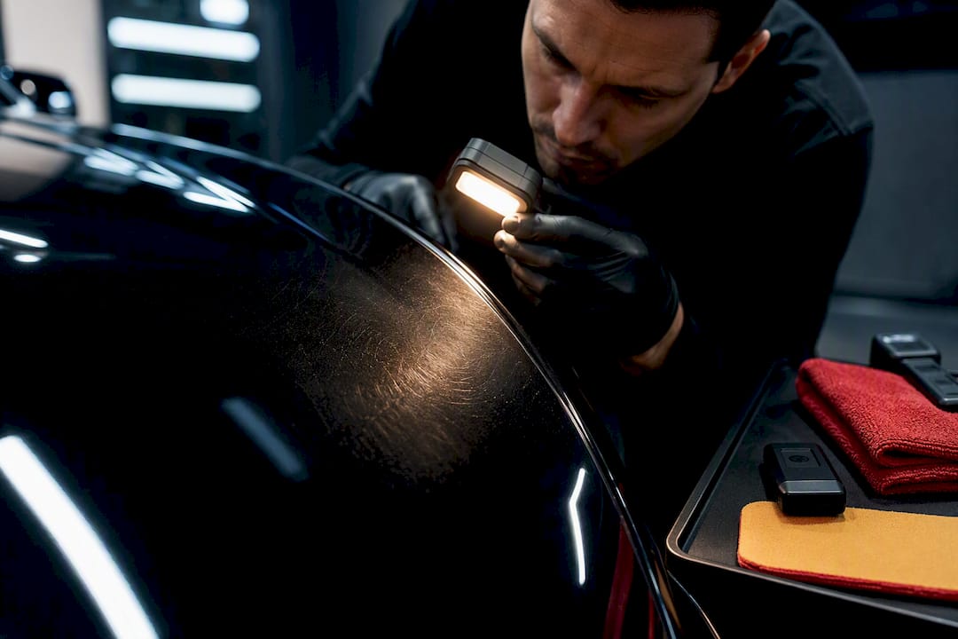 Detailer inspecting swirls on new car paint