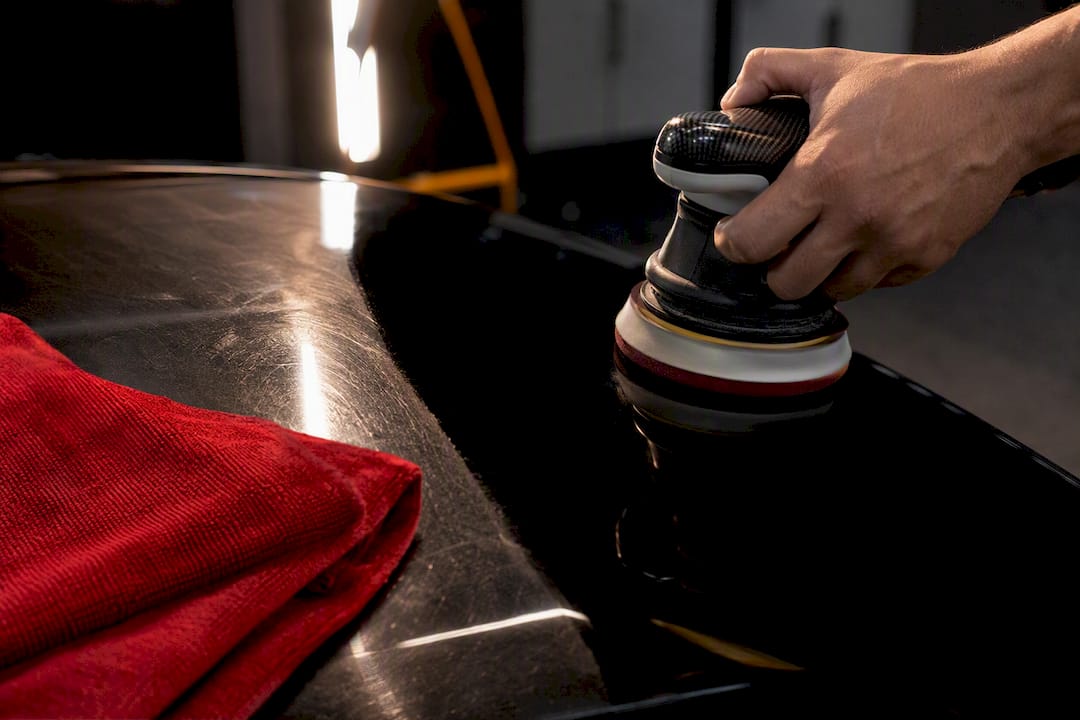 Technician polishing anonymous black vehicle panel