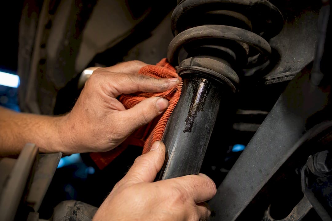 Technician wiping leaking shock absorber
