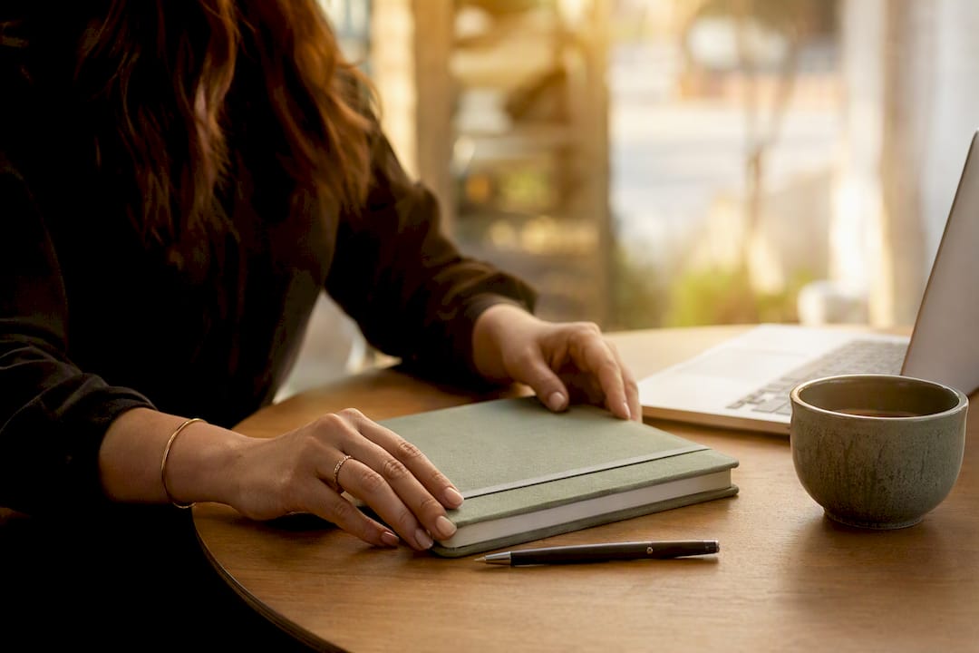 Hands organizing planner and pen on desk