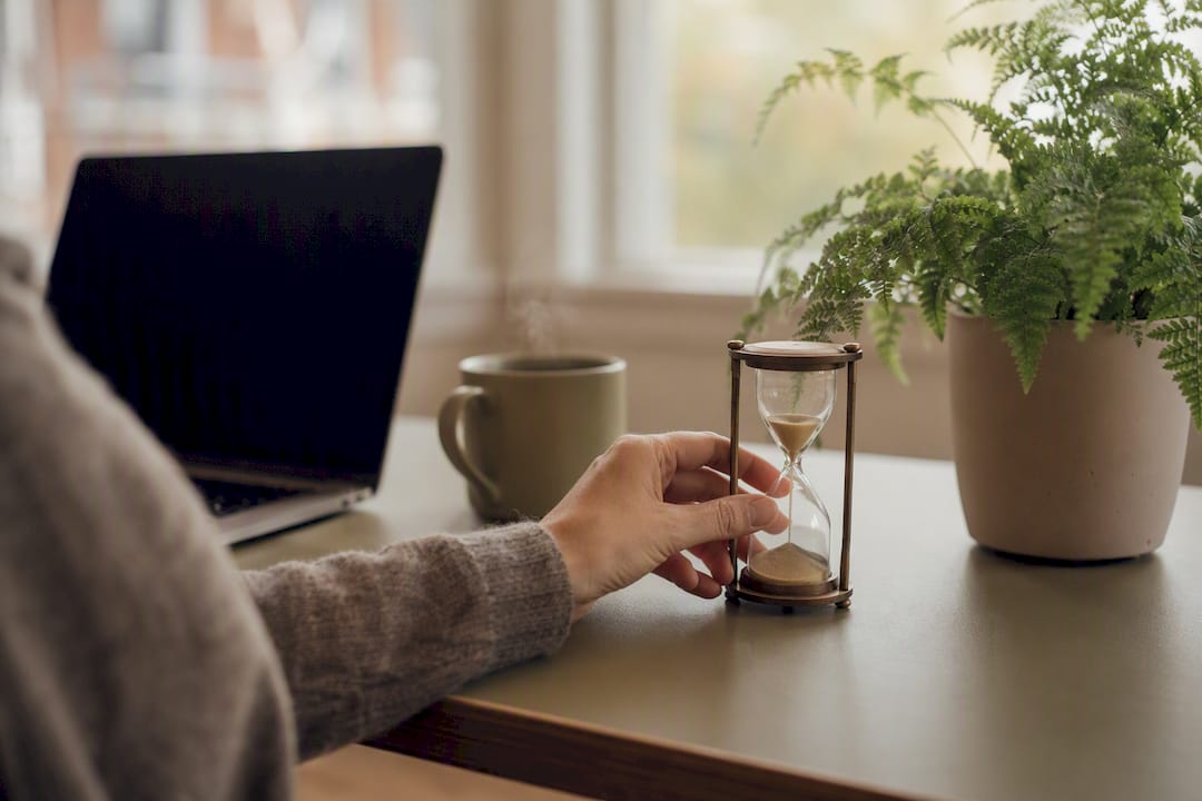 Workspace with hourglass and off laptop screen