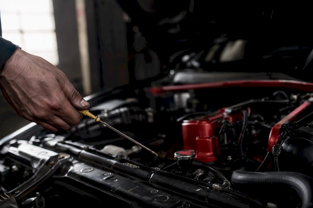 Hand inspecting engine oil dipstick in car