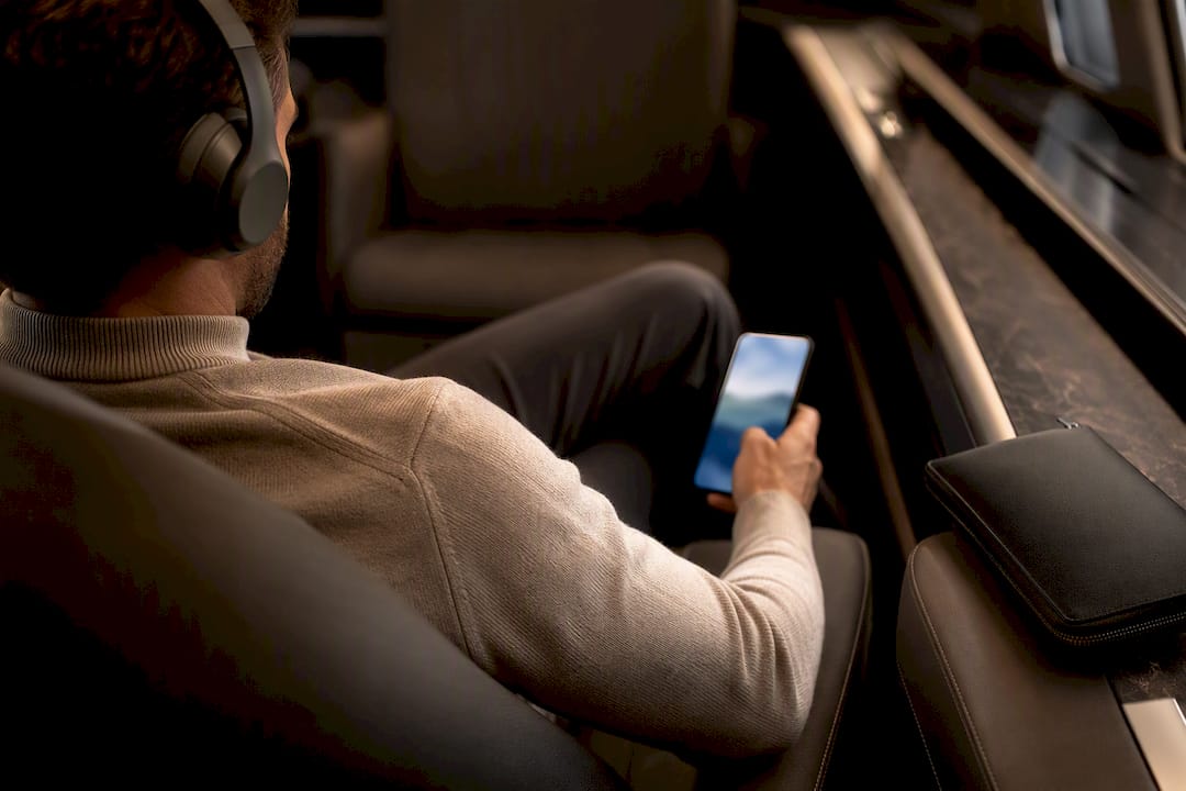 Passenger using headphones with phone in cabin