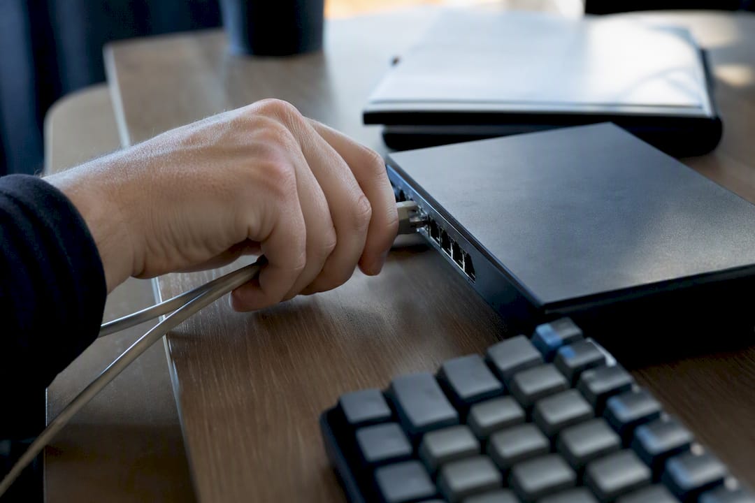 Hand steckt Netzwerkkabel im Büro ein