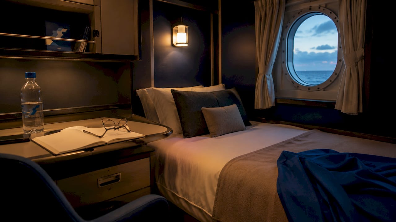 Interior cruise ship stateroom with bed and desk view