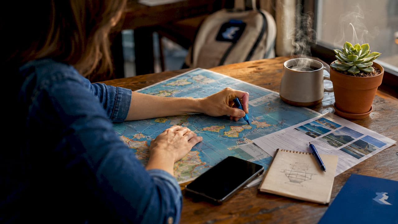 Hands placing pins on cruise map at home desk