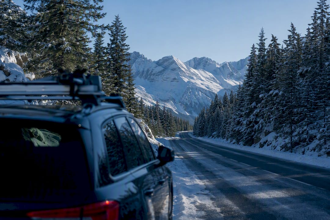 Verschneite Bergstraße mit fahrendem Auto