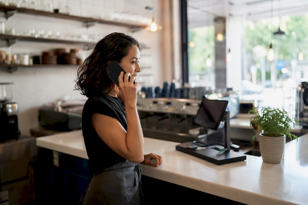 Business owner answering phone at store counter