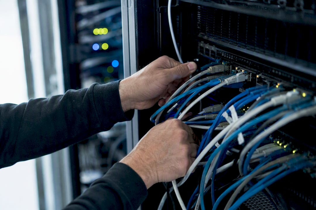 Hands connecting network cables to server ports