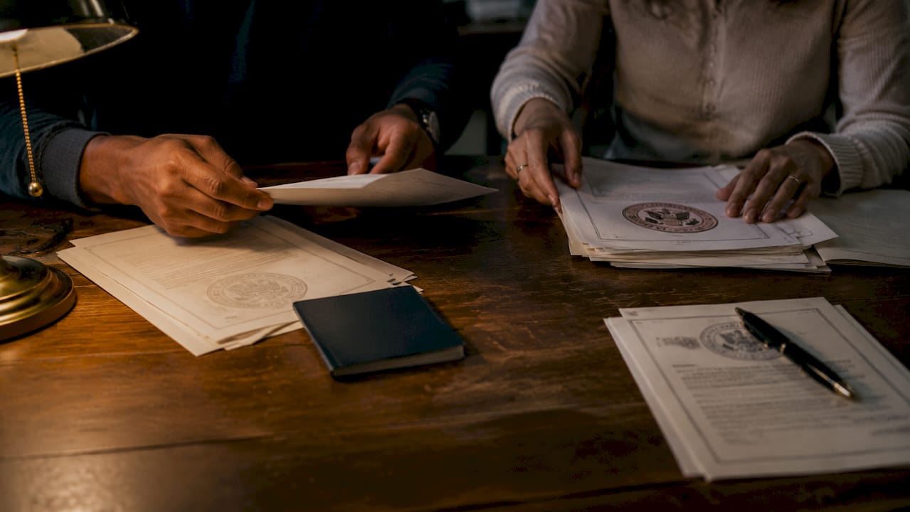Hands organizing official documents on library table