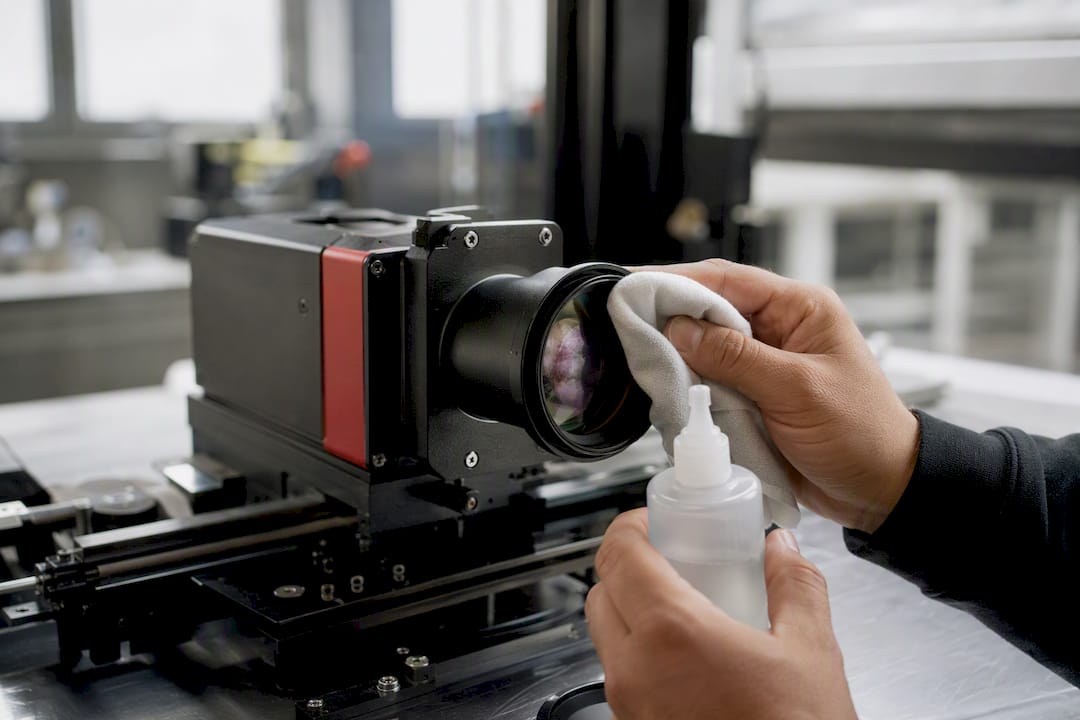 Mano che pulisce la lente della macchina per incisione laser